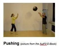 A woman and man toss a medicine ball back and forth during a fitness session.