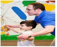 Adult guides a young boy with autism in a physical activity session.