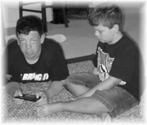 Two boys sitting on the floor playing a handheld video game.