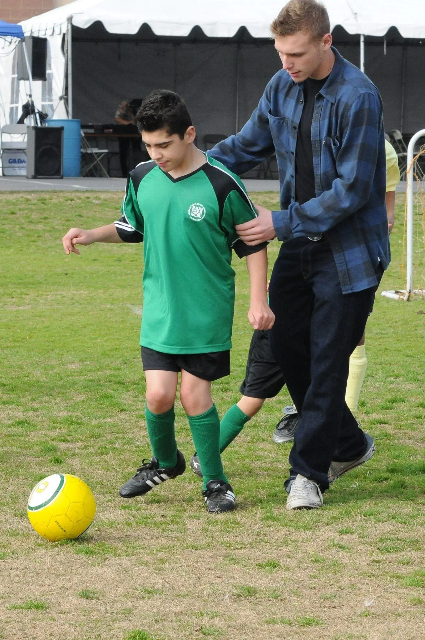 Volunteer buddy supporting a young soccer player on the field during an AYSO VIP practice.
