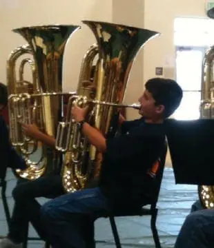 Boy playing a tuba in an ensemble.
