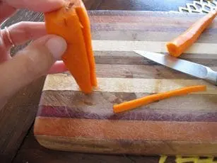 Carrot pieces are prepared on a cutting board for a recipe.