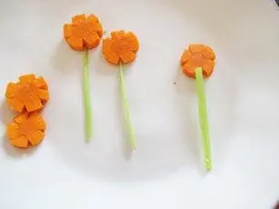 Carrot flowers with celery stems arranged on a white plate.
