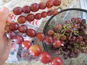 Grapes threaded onto wooden skewers next to a bowl of grapes.