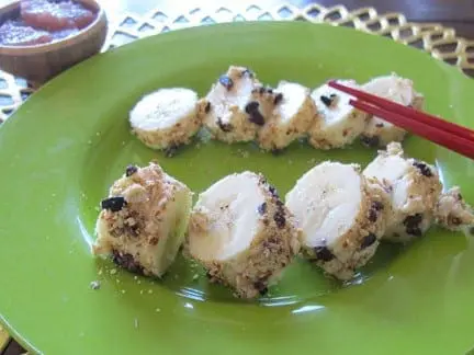 Banana pieces are rolled in toppings and arranged on a green plate with chopsticks.
