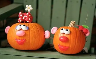 Two pumpkins decorated to resemble Mr. and Mrs. Potato Head with attached eyes, noses, mouths, and ears.