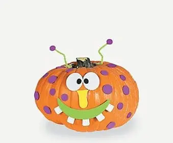 Orange pumpkin decorated as a monster with purple polka dots, googly eyes, a yellow nose, and a green smiling mouth.