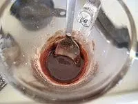 Cocoa powder and sugar are mixed with a spoon in a glass bowl.