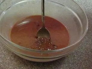 Chocolate mixture being stirred in a clear bowl with a spoon.