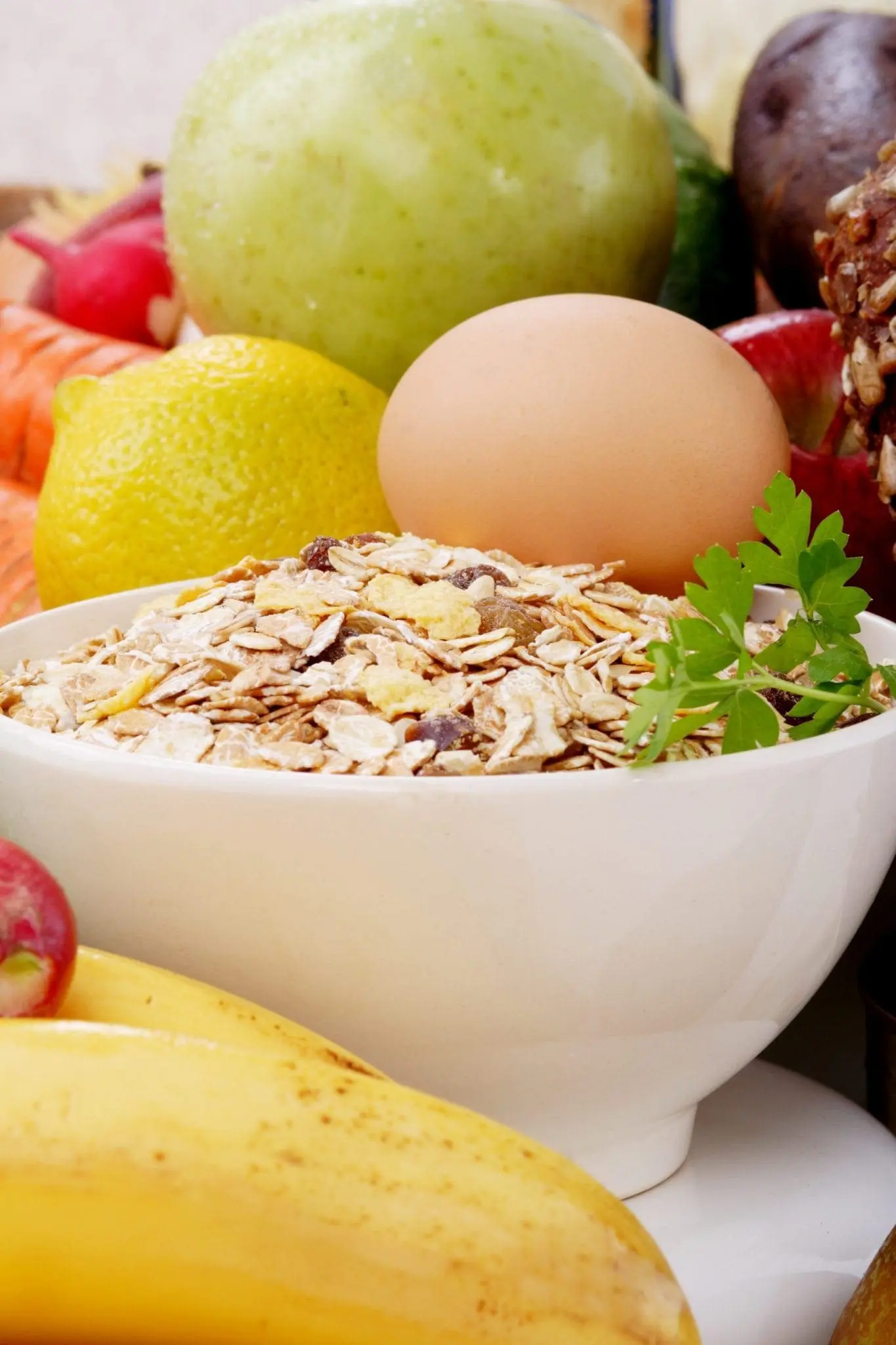 Bowl of oatmeal with an egg and various fruits and vegetables.