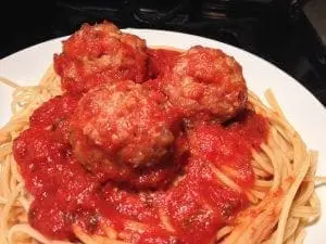 Three turkey meatballs covered in tomato sauce on a bed of spaghetti.