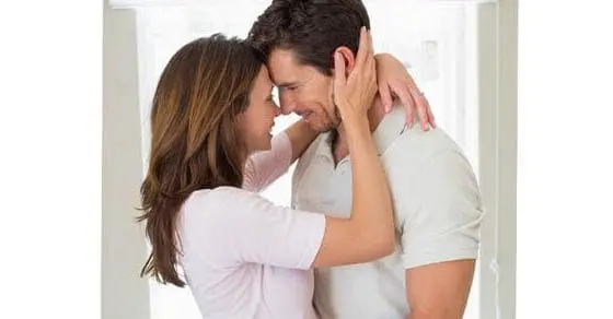 Couple embracing intimately with foreheads touching.