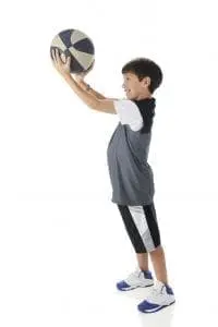 Boy holding a basketball above his head.