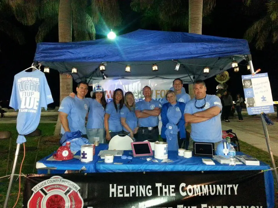 Pete Villasuso and station members stand behind a table at an event for Autism Speaks.