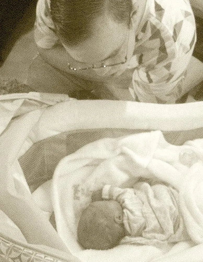 Christian looks down at a baby in a bassinet.