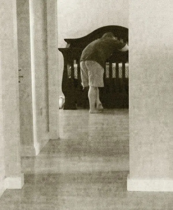 Christian bending over a crib.