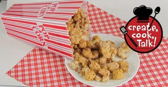 Cheesy" cauliflower popcorn spilling out of a popcorn box onto a plate.