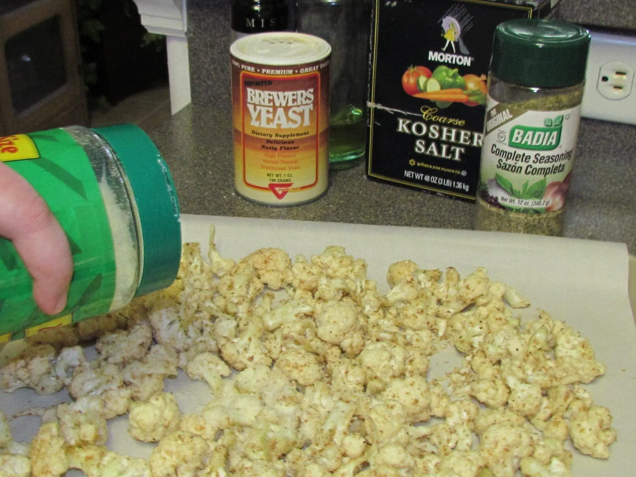 Cauliflower florets being seasoned for "cheesy" cauliflower popcorn