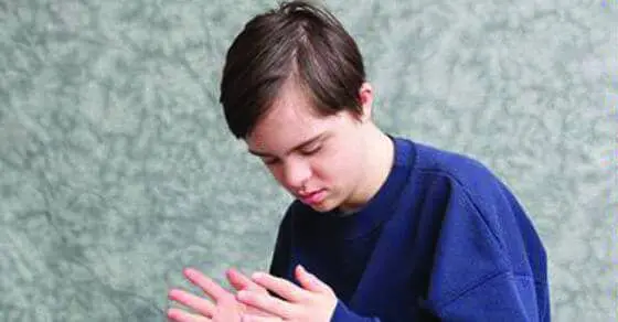 A young person looks down at their hands.