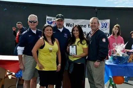 Four adults stand together in front of a banner that reads "Welcome to AYSO VIP Soccer.
