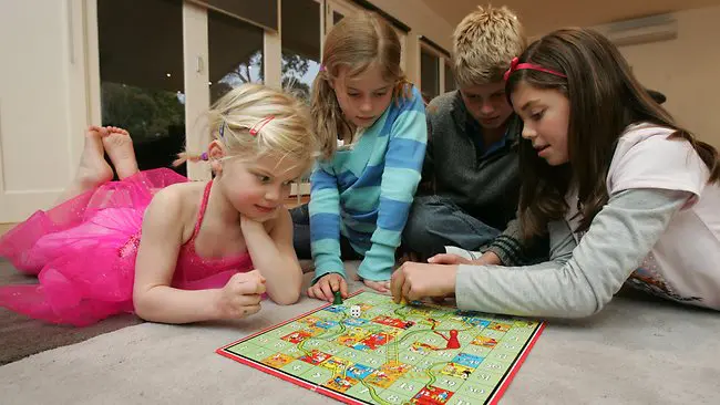 Four children playing a board game on the floor.