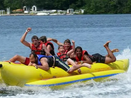 A group of people ride a yellow inflatable banana boat on the water.