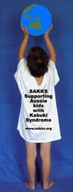 Child in a white shirt holding a globe, with text about supporting kids with Kabuki Syndrome.