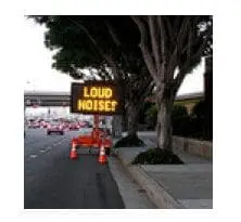 A digital sign on a roadside reads "LOUD NOISES".