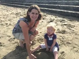 Tara Davenport-Miles crouching in the sand with a child.