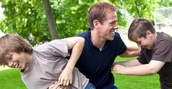 Father and two sons playing together outdoors.
