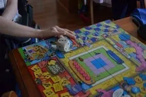A hand rests on a colorful board game with dice on it.
