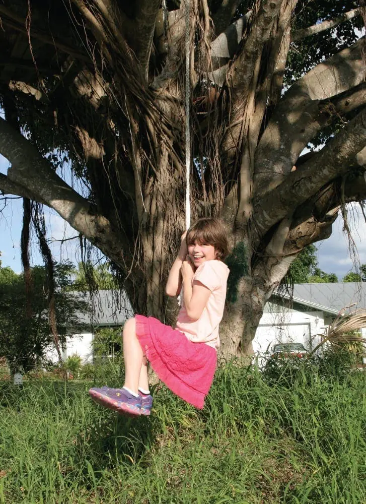 Nikki swinging on a rope in a large tree.
