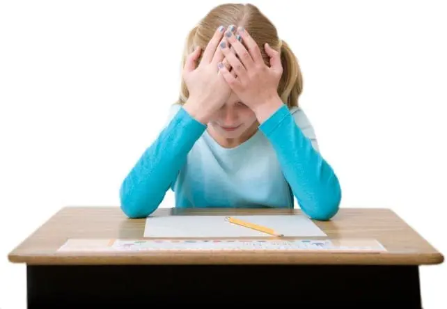 Girl with hands over her face at a desk with a test.
