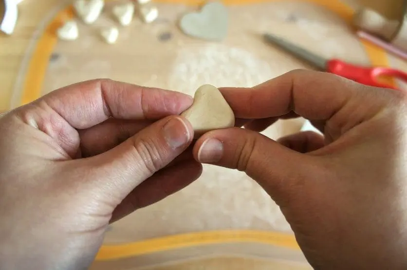 Hands shaping a heart from air-dry clay.