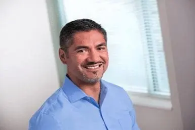 Pedro-Leon, a man with short, dark hair and a goatee, smiles in a blue collared shirt.