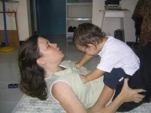 Woman doing sit-ups with a child on her stomach.
