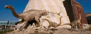 Four dinosaur sculptures in front of a building.
