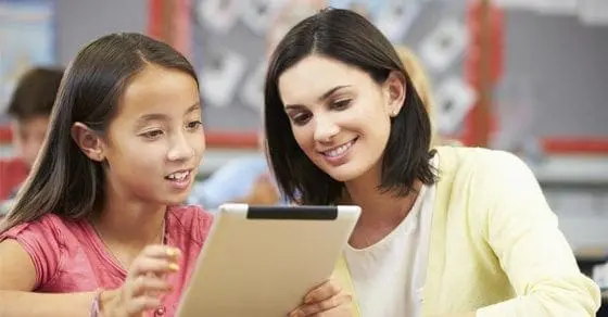 A teacher and student look at a tablet together.