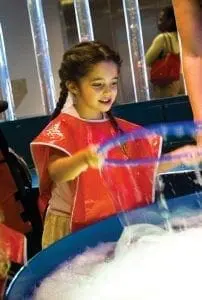 Girl in a red smock playing with bubbles.