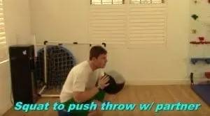 A man performing a squat to push throw with a medicine ball.
