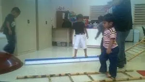 Children participate in an obstacle course with a balance beam.