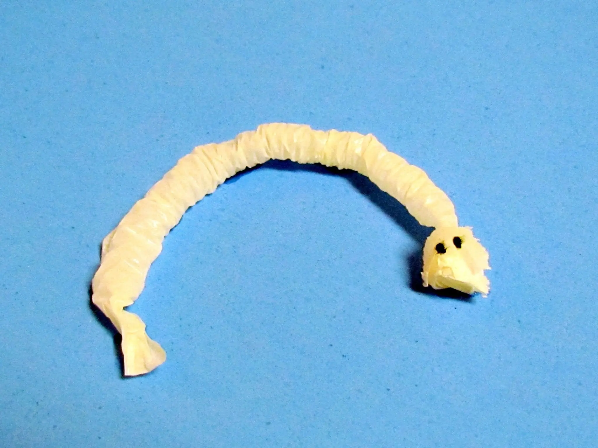 A wiggly worm made from a squished straw wrapper with two eyes.