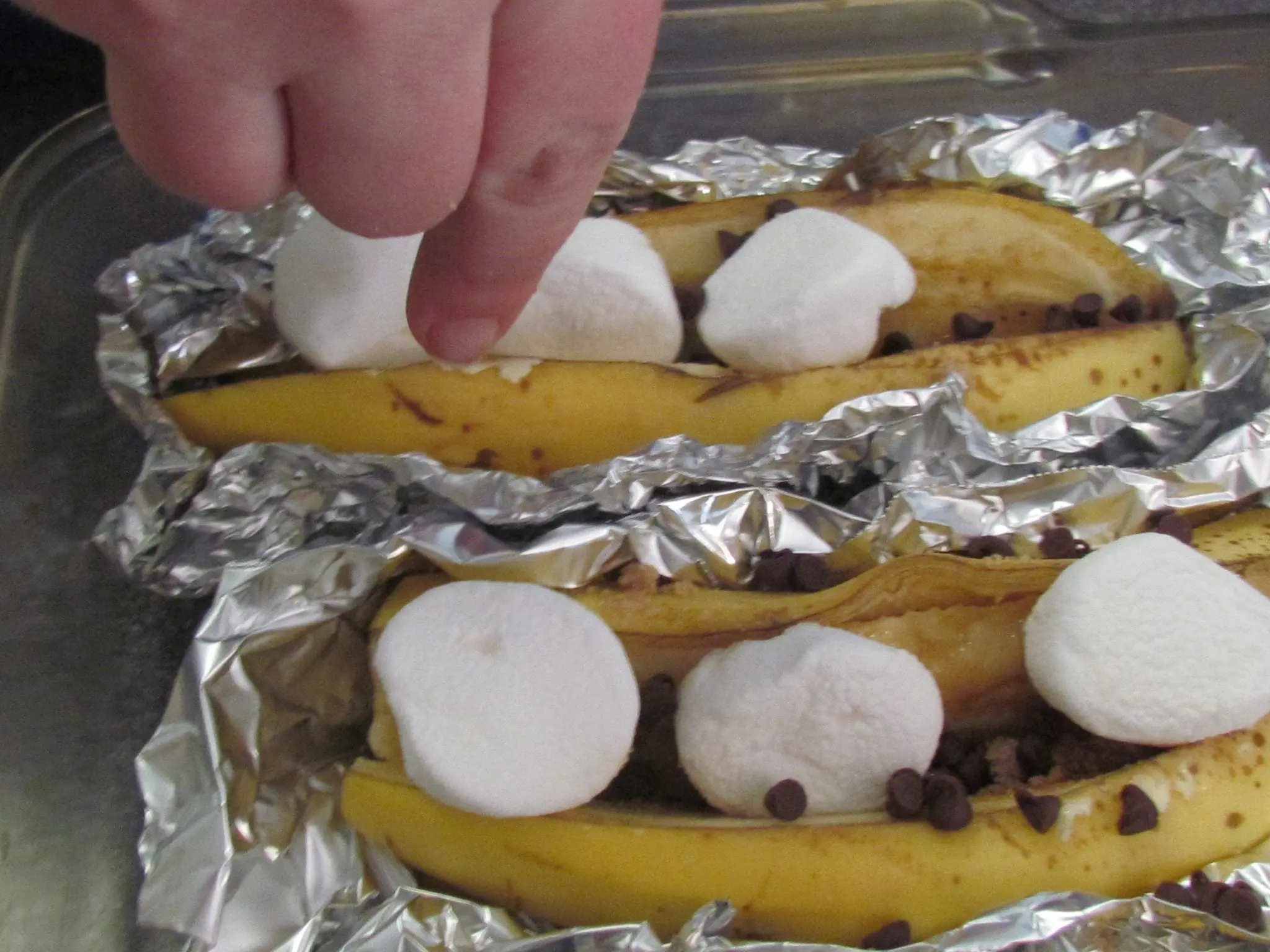 Bananas are prepared in tinfoil with chocolate chips and marshmallows.
