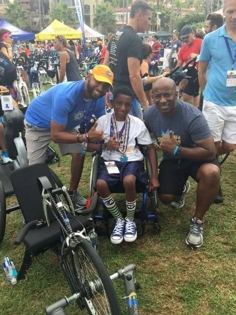 Kelvin Fields with two men and a boy in a wheelchair at an event.