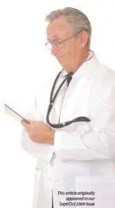 Doctor in a lab coat with a stethoscope around his neck reads a tablet.