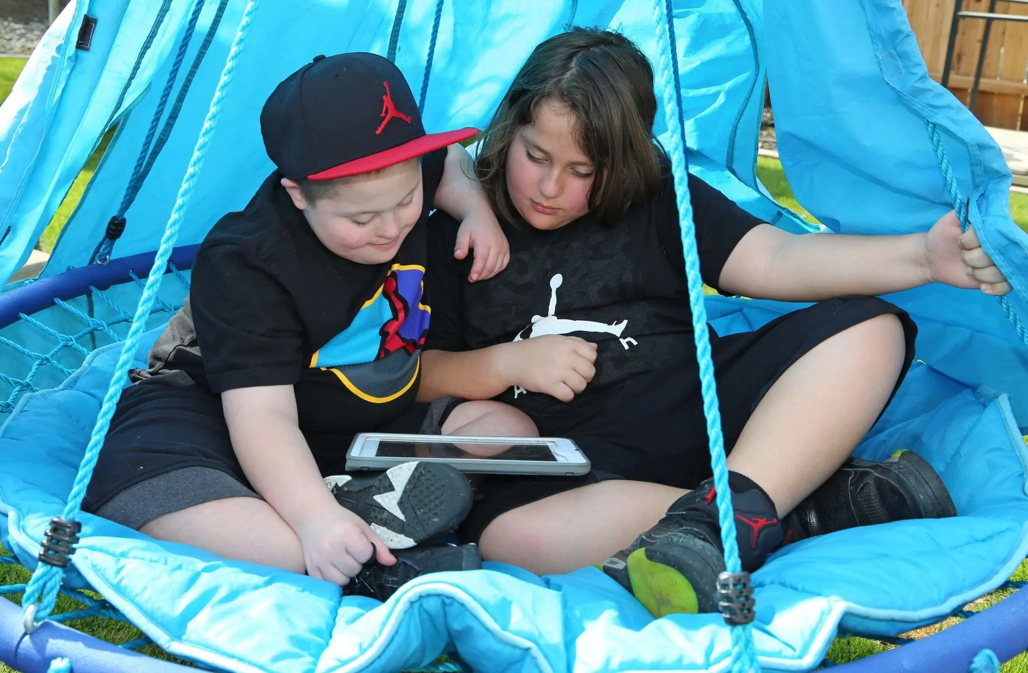 Sam De La Cerda and his brother Elijah sitting together with a tablet.