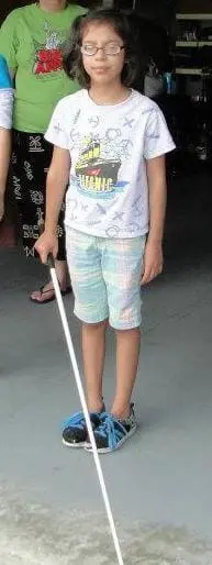 Torrie holding a white mobility cane.