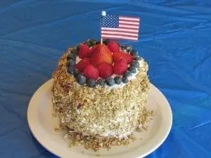 A no-bake watermelon cake decorated with berries and an American flag.