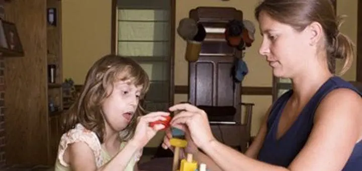 Woman working with a child on a building toy.