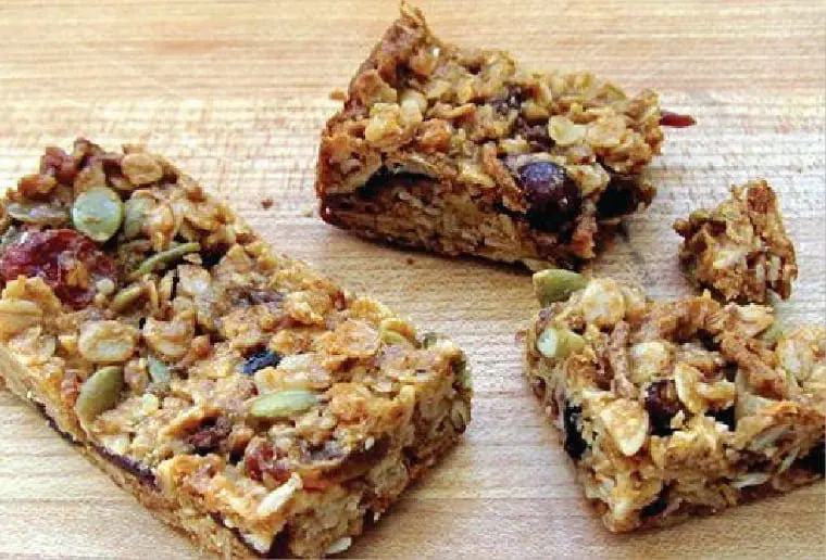 Three breakfast bars made with oats, seeds, and dried fruit.